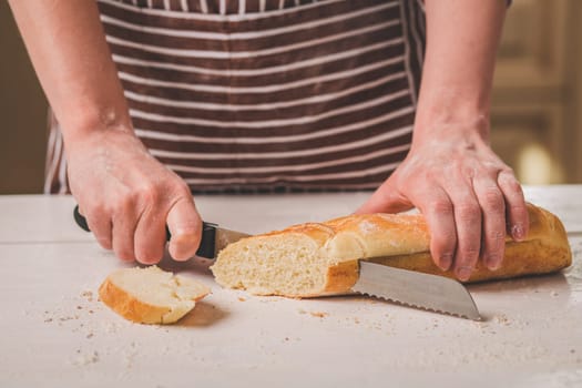 Woman cutting bread on wooden board. Bakehouse. Bread production. A woman in a striped apron