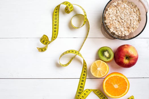 Fitness concept with fruit, bowl of oatmeal and centimeter. Top view background concept. Copy space
