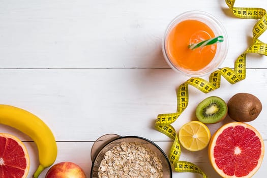 Fitness concept with fruit, bowl of oatmeal and centimeter. Top view background concept. Copy space