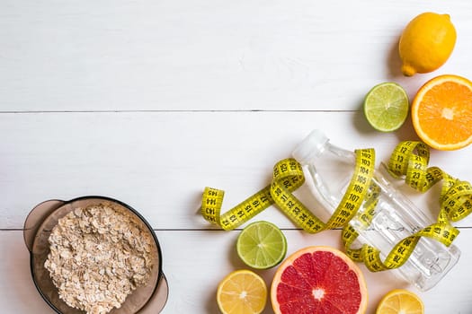 Fresh fruits with tape measure over white wooden background. Fitness concept. Top view. Copy space Flat lay