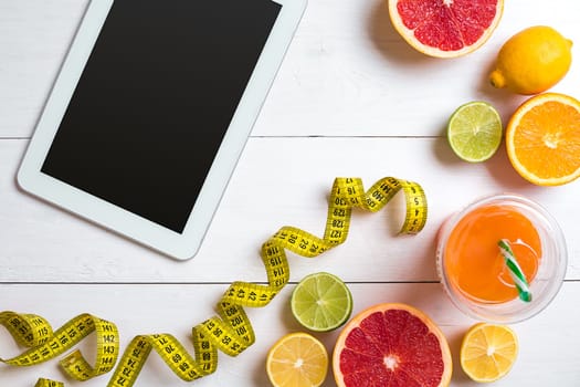 Fitness concept with fruit, bowl of oatmeal and centimeter. Top view background concept. Copy space. Tablet with a black screen
