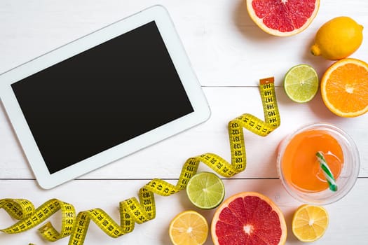 Fitness concept with fruit, bowl of oatmeal and centimeter. Top view background concept. Copy space. Tablet with a black screen