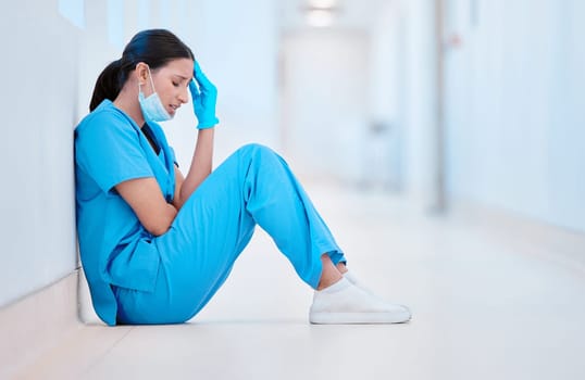 Everyone needs to cry. a young female nurse sitting on the floor looking depressed