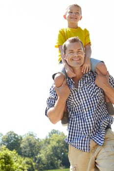 Enjoying the outdoors together. Young father carrying his son on his shoulders outdoors