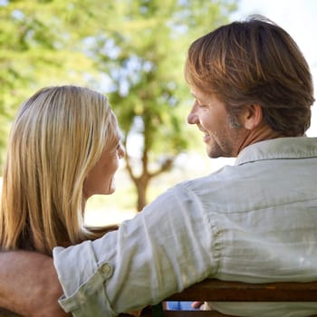 The beauty of nature is reflected in their love. Rear view shot of a happy mature couple sitting on a bench in the park