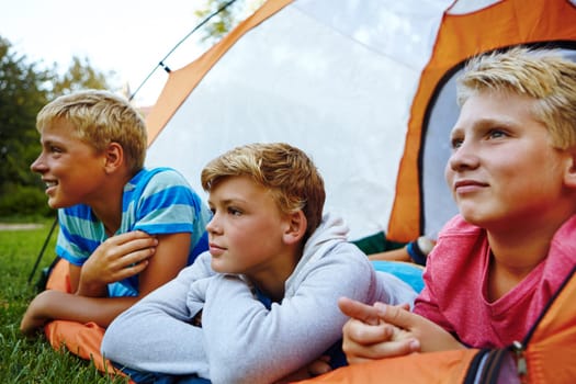 Loving summer camp. two young boys lying in their tent