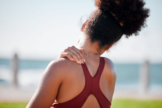 Medical, shoulder pain and fitness with black woman at beach for yoga, workout and exercise training. Burnout, injury and physical therapy with girl in city park for health, sport and pilates goals.