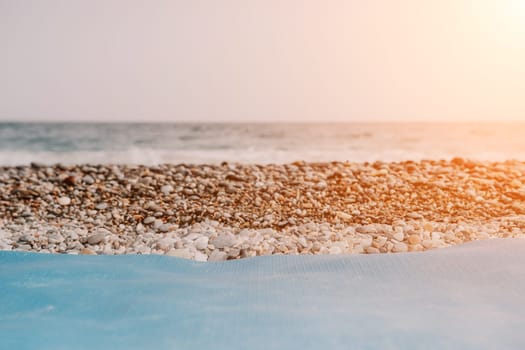 Blue yoga mat is on a sandy beach by the sea