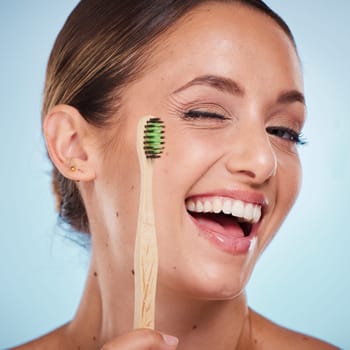 Brushing teeth, dental and woman with toothbrush, wink and beauty, oral health and fresh breath with studio background. Mouth wellness, Invisalign portrait and teeth whitening with bamboo brush