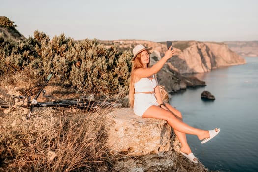 Woman travel sea. Young Happy woman in a long red dress posing on a beach near the sea on background of volcanic rocks, like in Iceland, sharing travel adventure journey