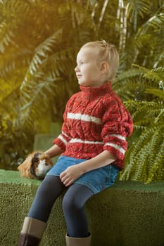Pretty blond girl posing in park with her pet, close-up