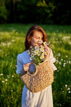 portrait of a beautiful, happy red-haired woman holding a basket of daisies in her hands. High quality photo