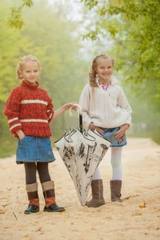 Image of cute smiling girlfriends walking in park
