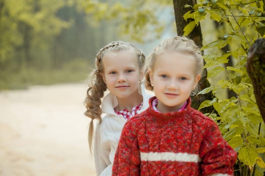 Image of two lovely girlfriends posing in park, close-up
