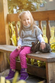 Pretty little girl sitting in gazebo with rabbit, close-up