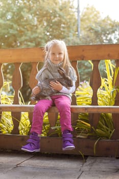 Smiling little girl posing in arbor with rabbit, close-up