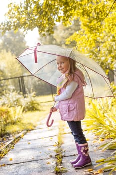 Slyly smiling girl posing under umbrella in park, close-up