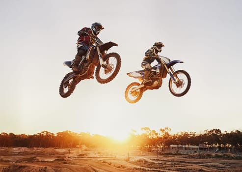Motorbike, jump and adventure during race for competition as transportation with sunset. Men, motorcycle and action for sports in the outdoor on fast course with power and moving fast with risk