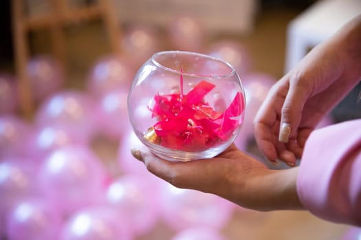 The pink-colored bows symbolize the breast cancer prevention movement for women and men. A woman holds a glass container in her hands.