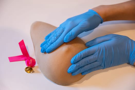 Recommended self-examination of the breast by applying pressure with both hands in the right way. Professional demonstration of grip on M counter phantom during breast examination.