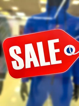 shopping background. Shopping, sales, concept. Sale clothing concept. Retail red tag with a large inscription SALE hanging on a window display in a clothing store. High quality photo