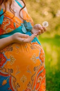 Hands mothers and fathers on the abdomen of a pregnant. A green dress.