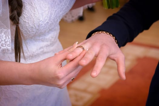 Newlyweds exchange rings, groom puts the ring on the bride's hand in marriage registry office