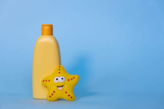 Yellow layout of a children's cosmetic product with a place for a logo and funny toy on a blue background. Baby shampoo, shower gel or body lotion. Space for text.