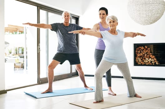 Yoga is a valuable habit to practice. an instructor guiding a senior couple in a yoga class