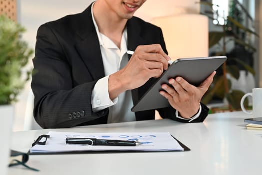 Smiling male entrepreneur analyzing sales statistics management on digital tablet screen.
