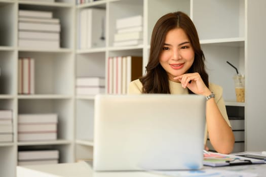 Confident female manager watching online webinar on laptop screen. Business, communicating and technology.