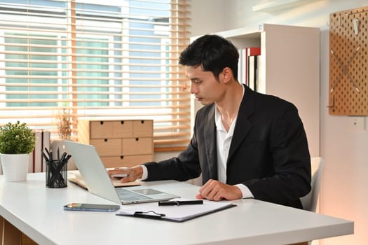 Focused businessman entrepreneur working on online marketing, using laptop at working desk.