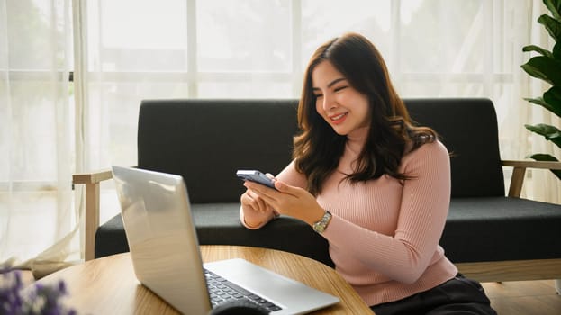 Relaxed young woman using smartphone communication in social media while sitting in living room.