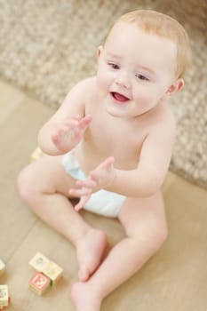 Lets do the clapping song now. A cute little boy clapping his hands with his blocks lying next to him