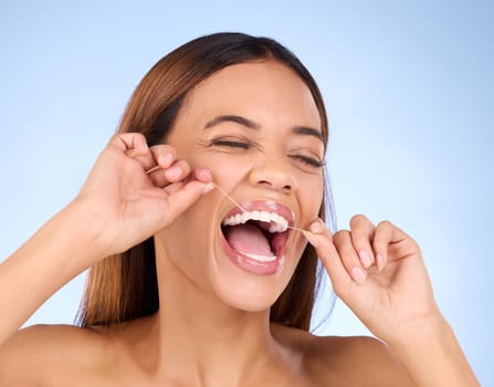 Dental floss, tooth cleaning and woman smile with teeth hygiene, healthcare and wellness treatment. Isolated, blue background and studio with a female feeling beauty from a clean mouth with self care.