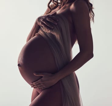 Woman, pregnant and fabric on stomach in studio with hands, touch and art by white background. Pregnancy model, shadow and mom wellness with cloth for body, belly and silhouette with dark aesthetic.
