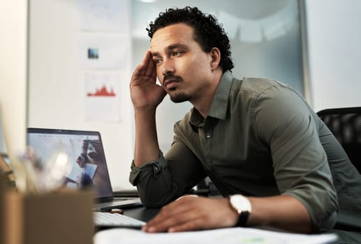 Come on, think. a handsome young businessman sitting alone in the office and feeling stressed while using his computer