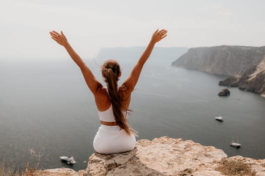 Middle aged well looking woman with black hair doing Pilates with the ring on the yoga mat near the sea on the pebble beach. Female fitness yoga concept. Healthy lifestyle, harmony and meditation.