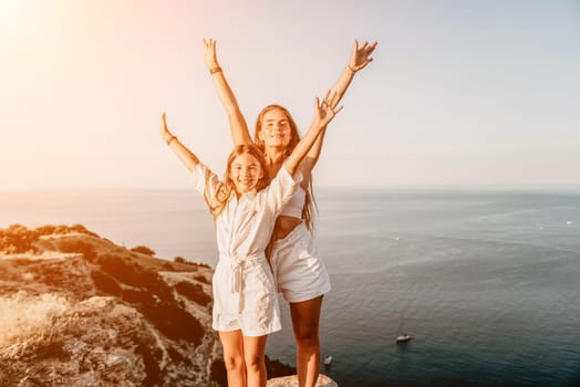 Close up portrait of mom and her teenage daughter hugging and smiling together over sunset sea view. Beautiful woman relaxing with her child.