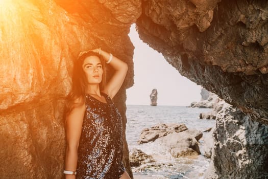 Woman travel sea. Young Happy woman in a long red dress posing on a beach near the sea on background of volcanic rocks, like in Iceland, sharing travel adventure journey