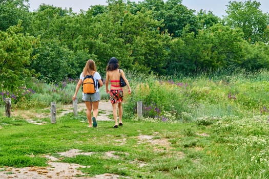 go from one place to another, typically over a distance of some length. Two cute girlfriends travel by rural roads and blossoming nature.