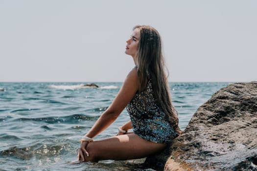 Woman travel sea. Young Happy woman in a long red dress posing on a beach near the sea on background of volcanic rocks, like in Iceland, sharing travel adventure journey