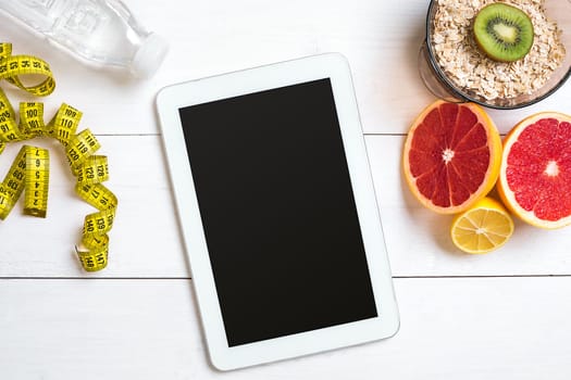 Fresh fruits with tape measure over white wooden background. Fitness concept. Top view. Copy space Flat lay