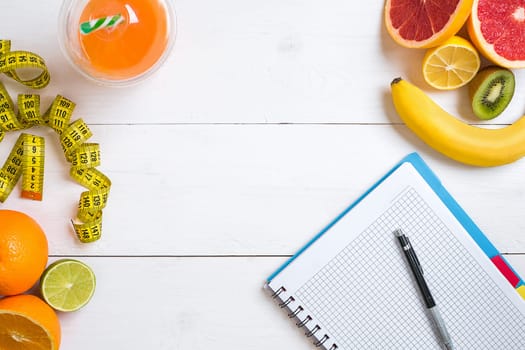 Fitness concept with fruit, bowl of oatmeal and centimeter. Top view background concept. Copy space. Pen and notepad for notes