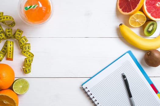 Fresh fruits with tape measure over white wooden background. Fitness concept. Top view. Copy space Flat lay