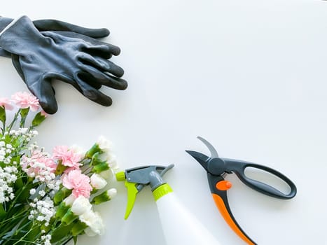 spray pink and white flowers with gardening tools on white background