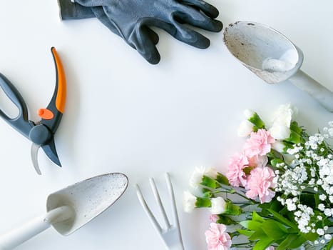 spray pink and white flowers with gardening tools on white background