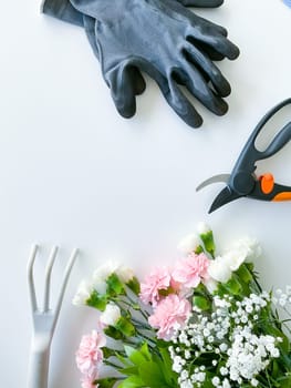 spray pink and white flowers with gardening tools on white background