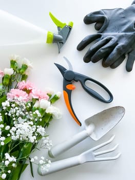 spray pink and white flowers with gardening tools on white background