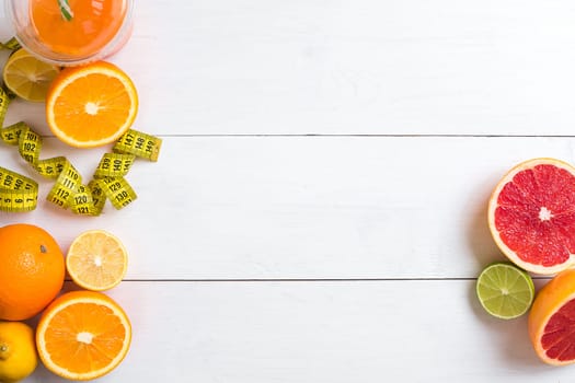 Fresh fruits with tape measure over white wooden background. Fitness concept. Top view. Copy space Flat lay
